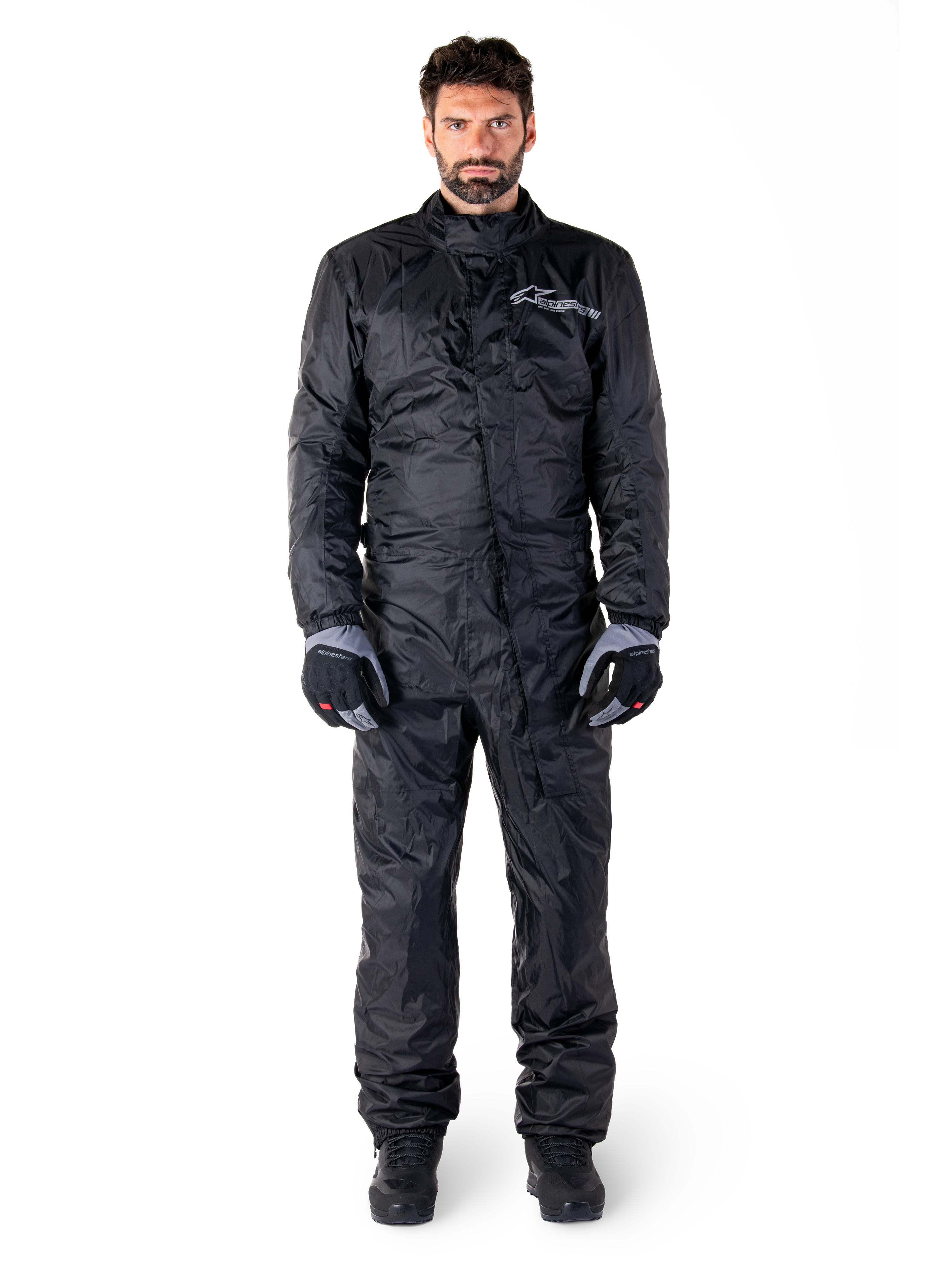 Alpinestars Hurricane Rain V2 Suit, Full-Body Motorcycle Rain Suit in Black, waterproof protective gear with high collar and front storm closure, featuring white logo on chest, worn with black and grey gloves and boots