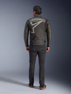 Veste Alpinestars Axton, veste de moto, Noir Anthracite Rouge Tangerine, vue arrière montrant un grand logo Alpinestars gris et un graphisme d'étoile, panneaux accordéon aux épaules, portée avec un pantalon noir et des chaussures noires décontractées.
