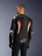 Veste Alpinestars T-GP Air en Noir Rouge Fluo, vue de trois-quarts arrière sur un mannequin, mettant en évidence la bosse aérodynamique, les protections externes Racing GP DFS aux épaules et aux coudes, les panneaux en mesh perforés au laser et les accents blancs et rouge fluo, veste de moto textile à coupe sport.