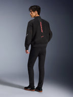 Modèle masculin portant la veste Alpinestars Flight Air en noir et rouge vif, vue arrière montrant le marquage vertical rouge au dos et la construction en maille 3D, associée à un pantalon noir et des baskets, style moto urbain