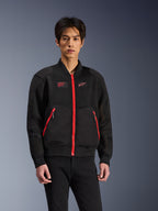Alpinestars Flight Air Jacket en noir et rouge vif, veste de moto urbaine de style bomber portée par un mannequin, avec panneaux de ventilation en maille, fermeture éclair avant rouge, détails de poches rouges et logo sur la poitrine, assortie à un pantalon noir