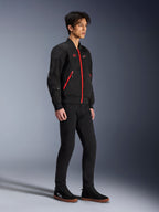 Veste Alpinestars Flight Air, Noir Rouge Vif, veste de moto urbaine de style bomber portée par un mannequin, dotée de panneaux en maille 3D et de fermetures éclair rouges contrastantes, associée à un pantalon noir et des chaussures de moto décontractées, équipement de protection moderne d'inspiration streetwear