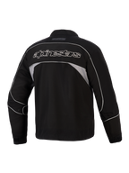 Alpinestars Unite Jacke, Rückansicht, Schwarz mit dunkelgrauen reflektierenden Einsätzen, weiß umrandeter Alpinestars-Schriftzug auf dem Rücken, urbane Motorrad-Softshelljacke mit minimalistischem Design