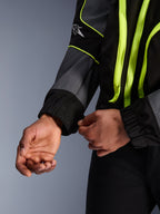 Alpinestars Unite Jacke, Urbane Motorradjacke, Schwarz und Asphalt mit neongelben Akzenten, Nahaufnahme von Händen, die den elastischen Ärmelbund anpassen, minimalistische von Streetwear inspirierte Schutzausrüstung