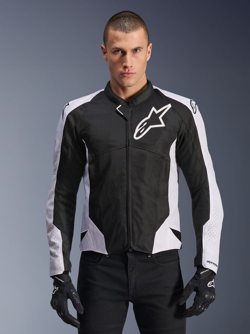 Alpinestars Viper Air V4 motorjas, sportieve motorjas, zwart en wit, gedragen door een rijder, tech mesh- en textielconstructie met witte schouderpanelen, opvallend sterlogo op de borst, sport-performance ontwerp, gecombineerd met zwarte motorhandschoenen