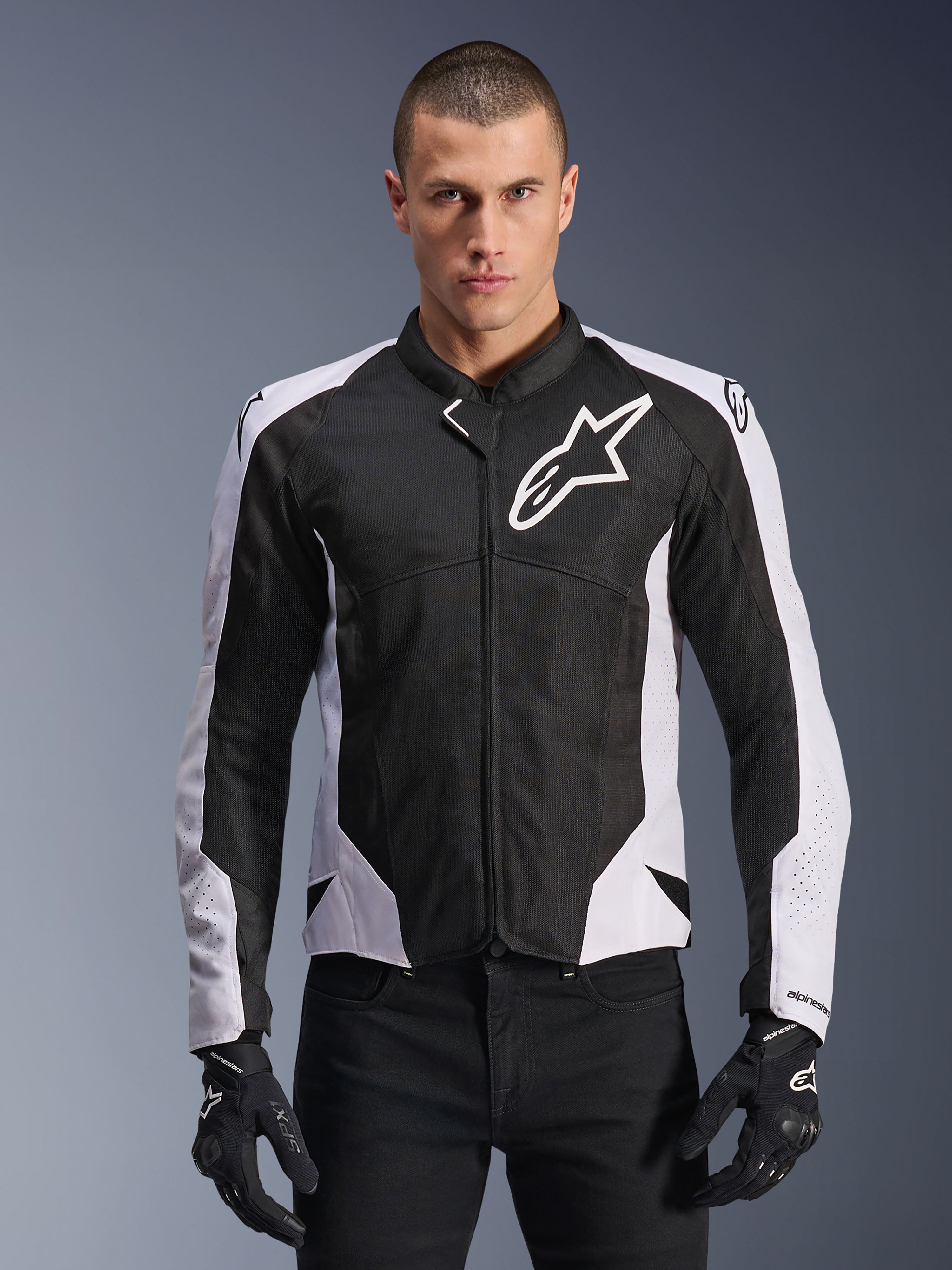 Alpinestars Viper Air V4 motorjas, sportieve motorjas, zwart en wit, gedragen door een rijder, tech mesh- en textielconstructie met witte schouderpanelen, opvallend sterlogo op de borst, sport-performance ontwerp, gecombineerd met zwarte motorhandschoenen