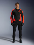 Modèle masculin portant la veste Alpinestars Viper Air V4 rouge fluo et noire, avec pantalon, gants et bottes de moto noirs, panneaux en maille respirante et logo étoile sur la poitrine, tenue de route sportive pour moto