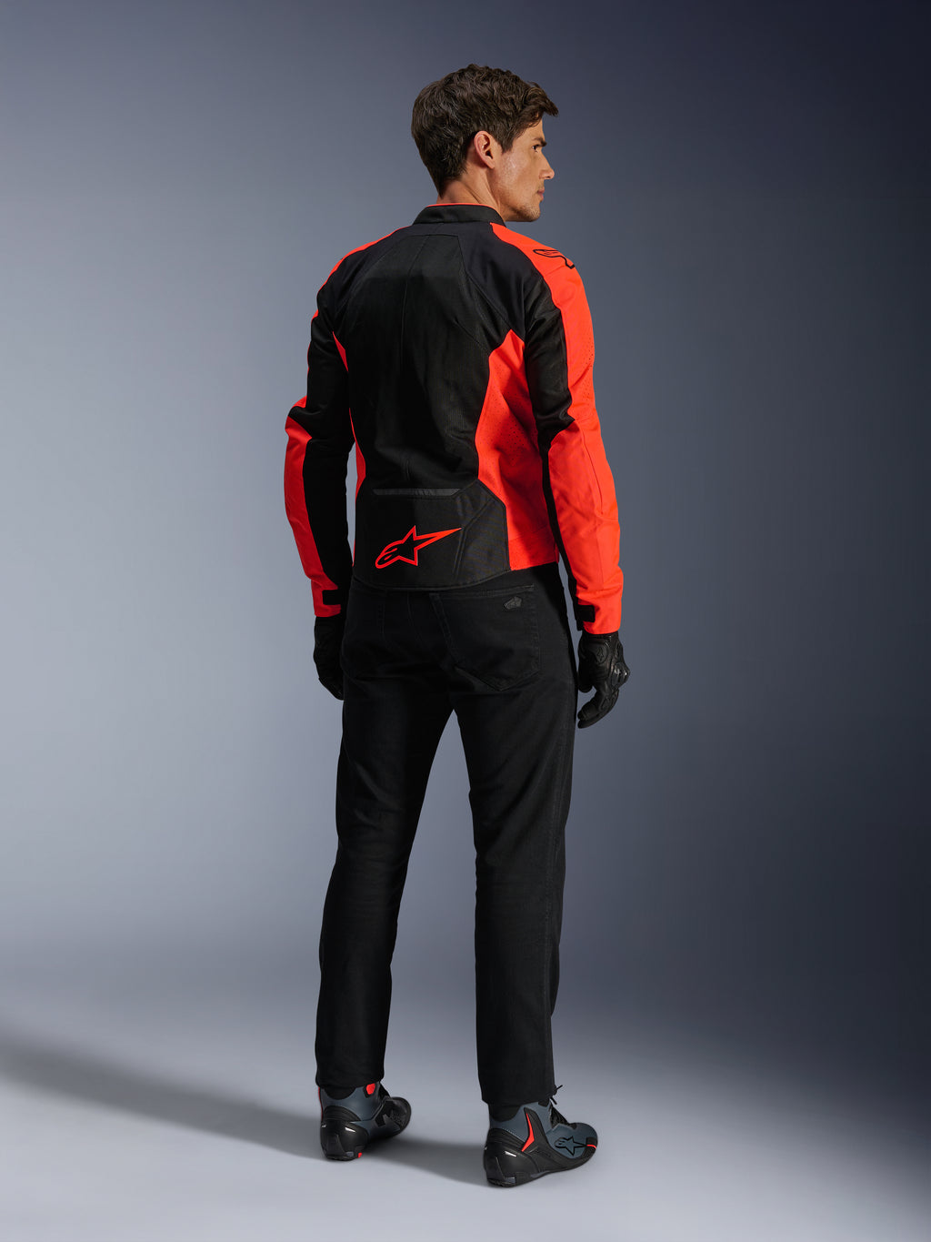 Veste Alpinestars Viper Air V4, Rouge Fluo Noir, vue arrière sur mannequin, présentant des panneaux en maille technique et un logo étoile rouge en bas du dos, associée à un pantalon et des gants de moto noirs pour un look de route complet.