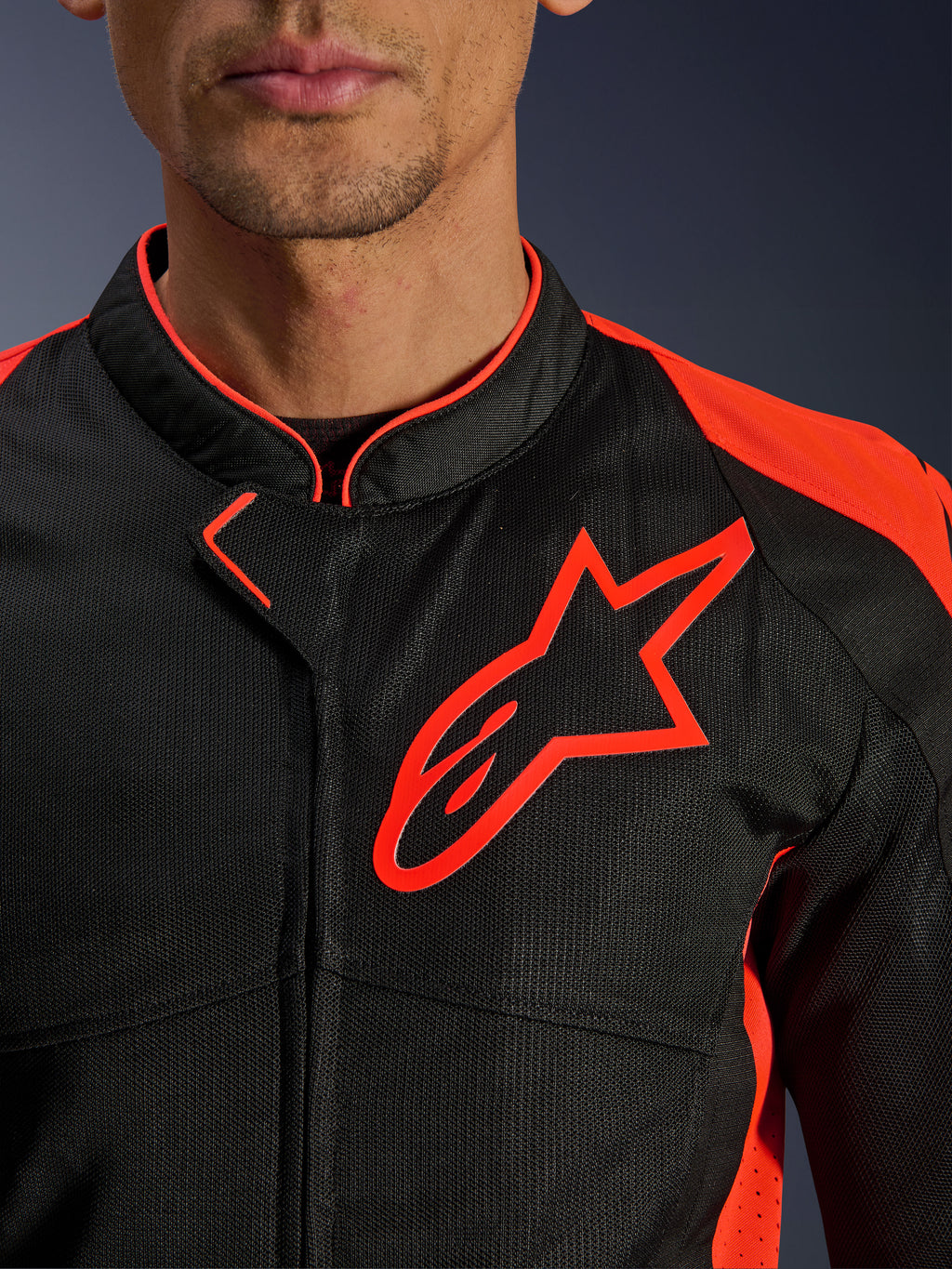 Veste Alpinestars Viper Air V4 en Noir et Rouge Fluo, vue rapprochée de la poitrine et du col, construction en maille technique noire, logo Alpinestars rouge proéminent, accents rouges vifs sur les épaules