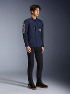 Alpinestars Dice Jacke, Dunkelblau und Schwarz, moderne Motorradjacke im Field-Style getragen von einem Model mit schwarzer Hose und schwarzen High-Top-Sneakern, mit mehreren Utility-Taschen, vertikalem Alpinestars-Branding am Ärmel und gewebten Aufnähern, urbane zeitgemäße Fahrerausrüstung