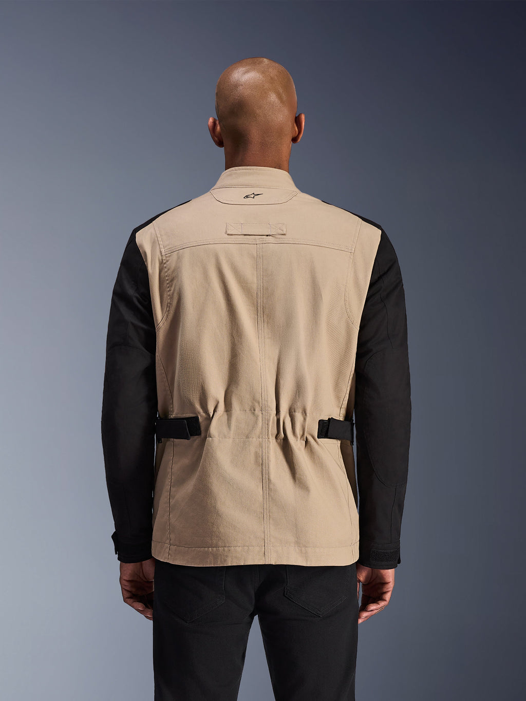 Veste Alpinestars Dice, veste de moto urbaine, aluminium et noir, vue de dos sur un mannequin, dotée d'épaules plissées pour la mobilité, de sangles de réglage à la taille et d'une construction robuste en sergé de polycoton.