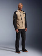 Veste Alpinestars Dice, veste de moto urbaine, Aluminum Black et Tan, design bicolore avec manches noires et buste kaki, portée par un mannequin avec un pantalon noir et des baskets noires, esthétique d'inspiration workwear avec poches utilitaires et marquage brodé sur la manche.