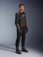 Männliches Model in der Alpinestars T-Sps Air V2 Jacke, Schwarz mit Red Fluo Akzenten, kombiniert mit schwarzer Motorradhose, schwarzen Handschuhen und schwarzen Stiefeln, sportliches Design mit Mesh-Einsätzen und weißen Alpinestars-Logos