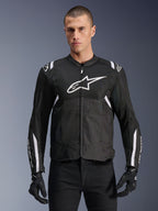 Alpinestars T-SPS Air V2 Jacke, Textil-Motorradjacke, Schwarz mit weißen Akzenten, großes weißes Brustlogo, perforiertes Mesh-Design für Belüftung, getragen mit schwarzer Hose und Handschuhen