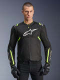Alpinestars T-Sps Air V2 Jacke in Schwarz Gelb Fluo, männliches Modell in belüfteter Textiljacke mit Mesh-Einsätzen und weißem Brustlogo, kombiniert mit schwarzen Motorradhandschuhen, urbane Motorradausrüstung