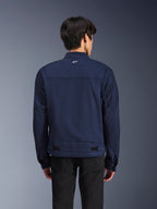 Veste Alpinestars Bruiser, veste de moto en textile bleu foncé, vue de dos sur mannequin, design d'inspiration workwear avec un petit logo Astars blanc sur la nuque, pattes de réglage à la taille, vêtement de moto urbain contemporain.