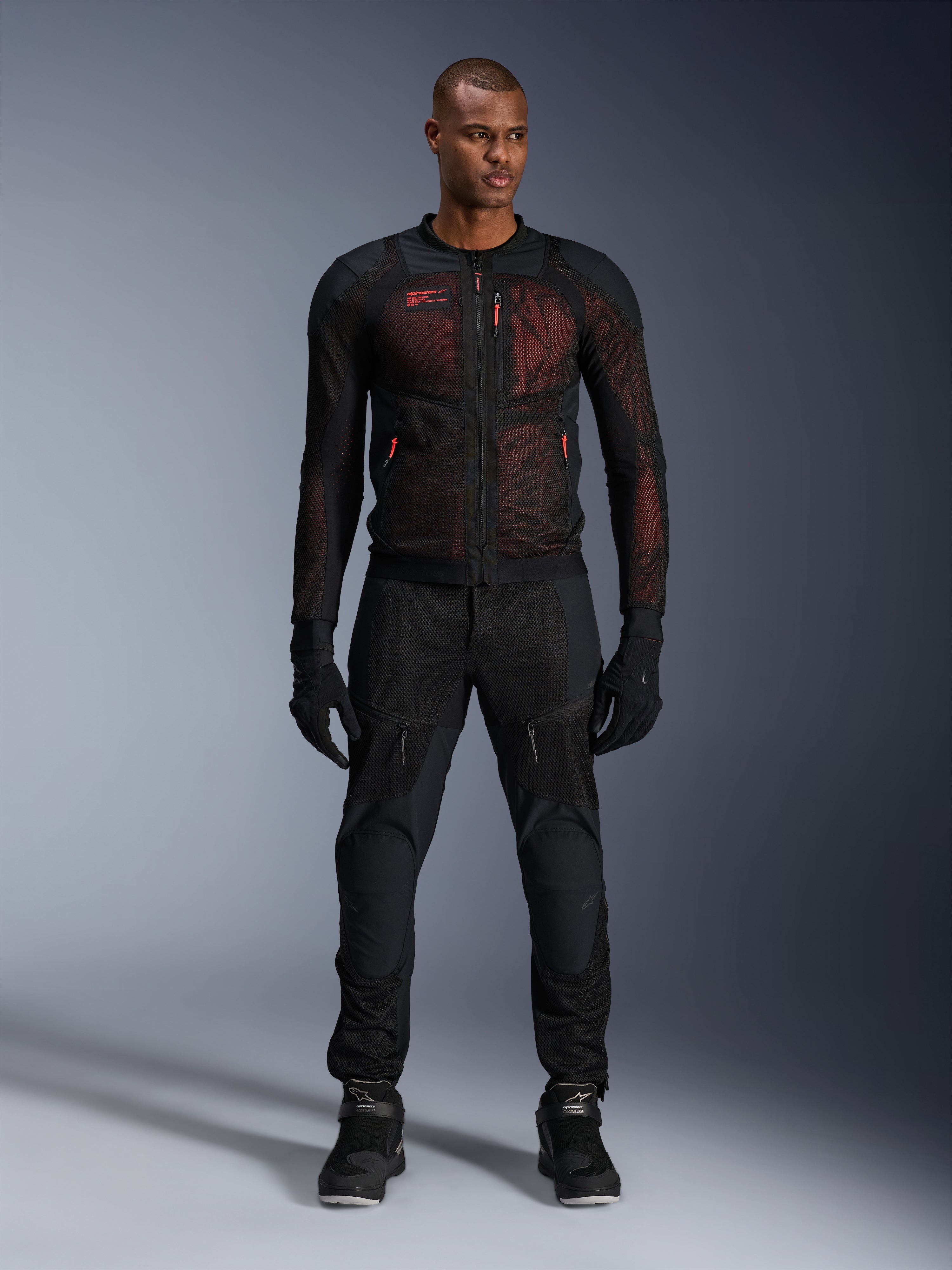 Alpinestars Troop-Air Pro Jacket, technische gepantserde luchtjas, Zwart en Red Fluo, gedragen door een mannelijk model met bijpassende motorbroek en handschoenen, voorzien van high-flow mesh-panelen en rode accenten, urban motorkleding
