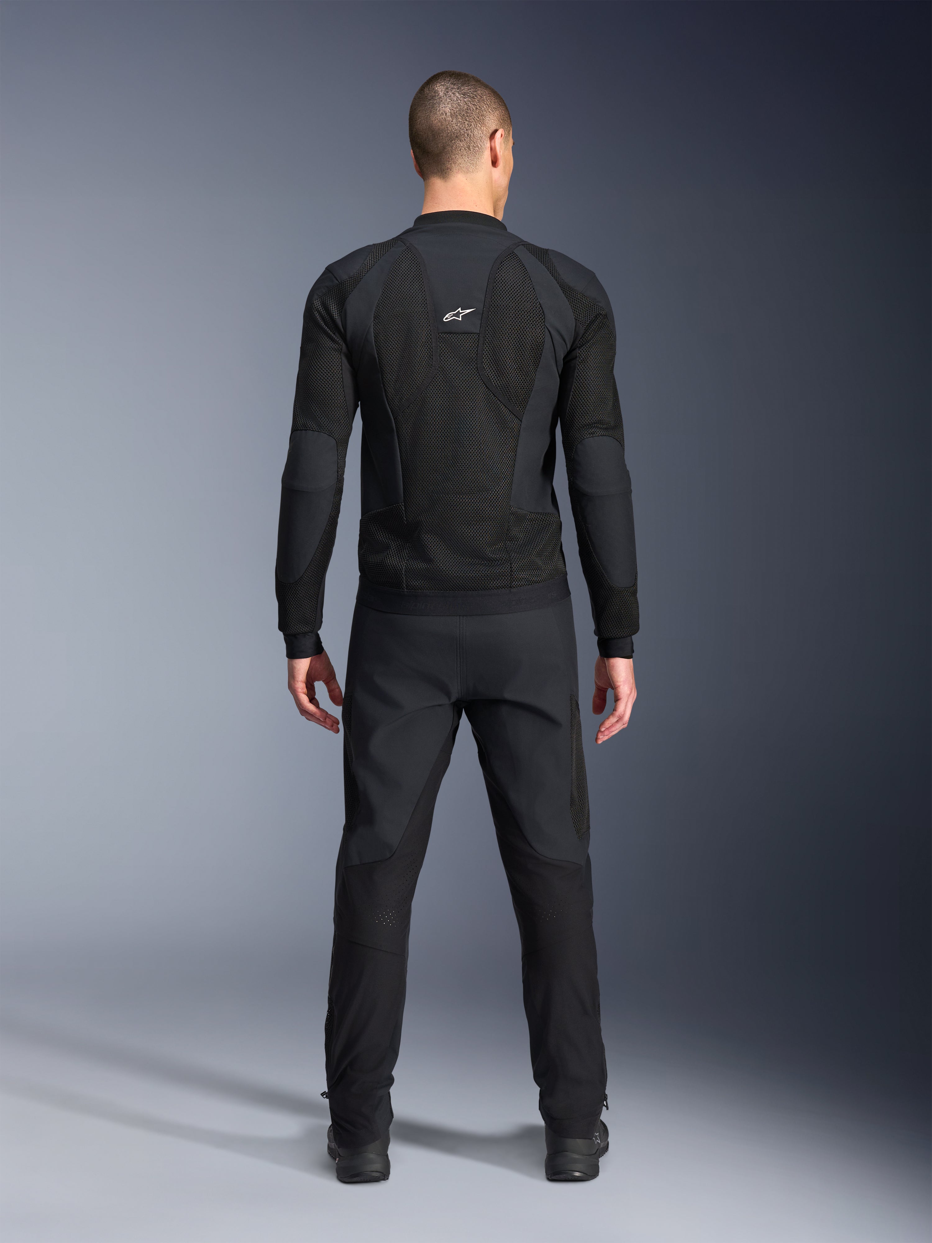 Alpinestars Troop-Air Pro Jacket, achteraanzicht, zwart, technische motorjas met grote mesh ventilatiepanelen en een wit Alpinestars-logo, gecombineerd met een zwarte broek, urban contemporary rijkleding