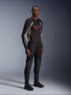 Alpinestars Troop-Air Jacke, technische Mesh-Motorradjacke in Schwarz, Ash Gray und Bright Red, getragen von einem Modell mit passender schwarzer Hose und Stiefeln, mit rotem Alpinestars-Logo auf der Brust, urbane zeitgemäße Motorradausrüstung.