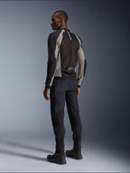 Model trägt Alpinestars Troop-Air Jacke in der Rückansicht, Schwarz, Aschgrau mit leuchtend roten Akzenten, technische Mesh-Konstruktion zur Belüftung, kombiniert mit schwarzer Motorradhose und Fahrstiefeln, urbaner zeitgenössischer Stil