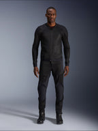 Mannelijk model in de Alpinestars Troop-Air Jas in Black Black, een lichtgewicht mesh motorjas gecombineerd met een bijpassende zwarte motorbroek en laarzen, voorzien van een technische 2D tech mesh-constructie voor superieure luchtstroom.