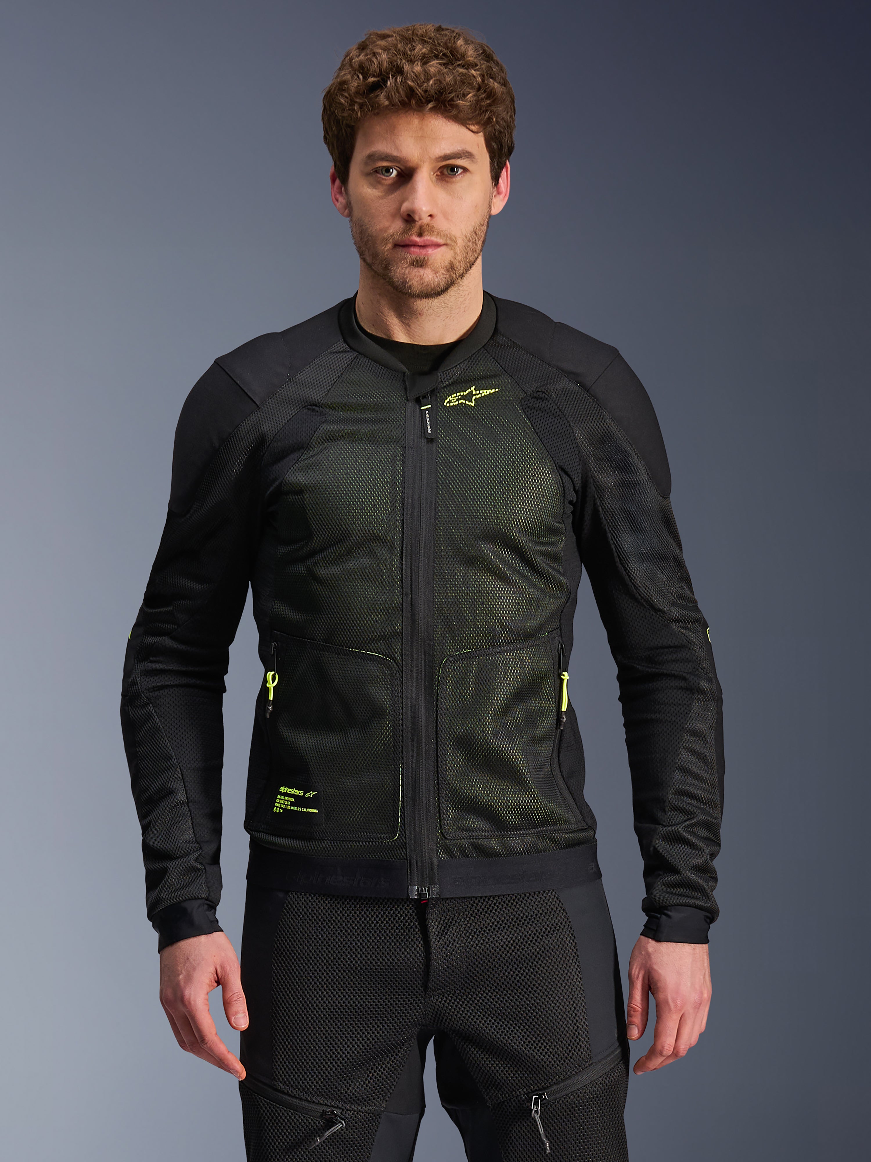 Alpinestars Troop-Air Jacket, zwart en neongeel, gedragen door mannelijk model, lichtgewicht mesh-constructie, neongele ritsen en branding, technische geventileerde motorjas voor stedelijk rijden