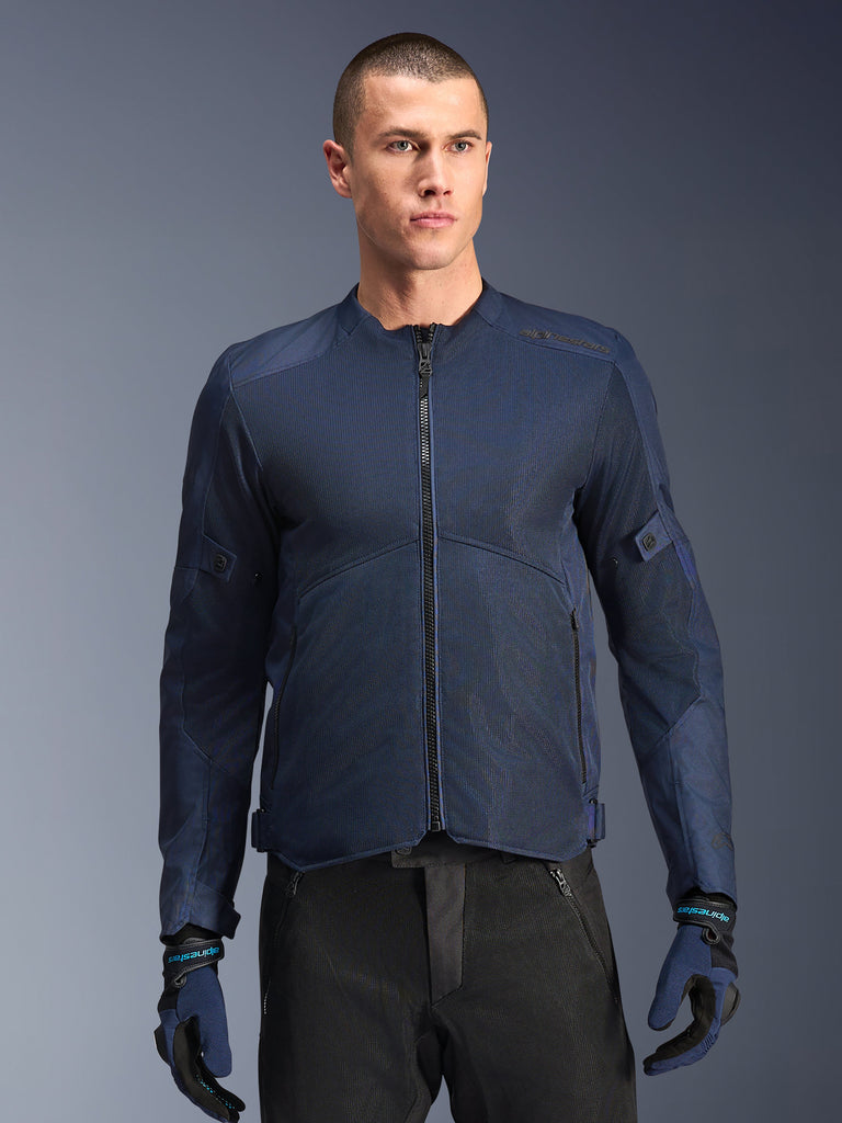Veste Alpinestars C-1 Air, veste de moto bleue, portée par un mannequin homme avec un pantalon noir et des gants assortis bleus et noirs, dotée de panneaux en maille technique pour la circulation de l'air, design urbain épuré avec fermeture éclair frontale et marquage discret