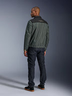 Veste Alpinestars Ignite Air en Gris Urbain Noir Bleu, vue de dos sur mannequin, dotée d'un corps en mesh avec un empiècement noir aux épaules et du texte blanc, poignets rayés, associée à un jean en denim foncé et des baskets noires, vêtement de moto style de vie urbain
