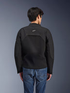 Alpinestars Provoke Jacke, Urbane Motorradjacke, Schwarz, Rückansicht mit weißem Astars-Logo und technischen Ripstop-Einsätzen, kombiniert mit blauen Denim-Jeans, modernes Design für den Stadtverkehr