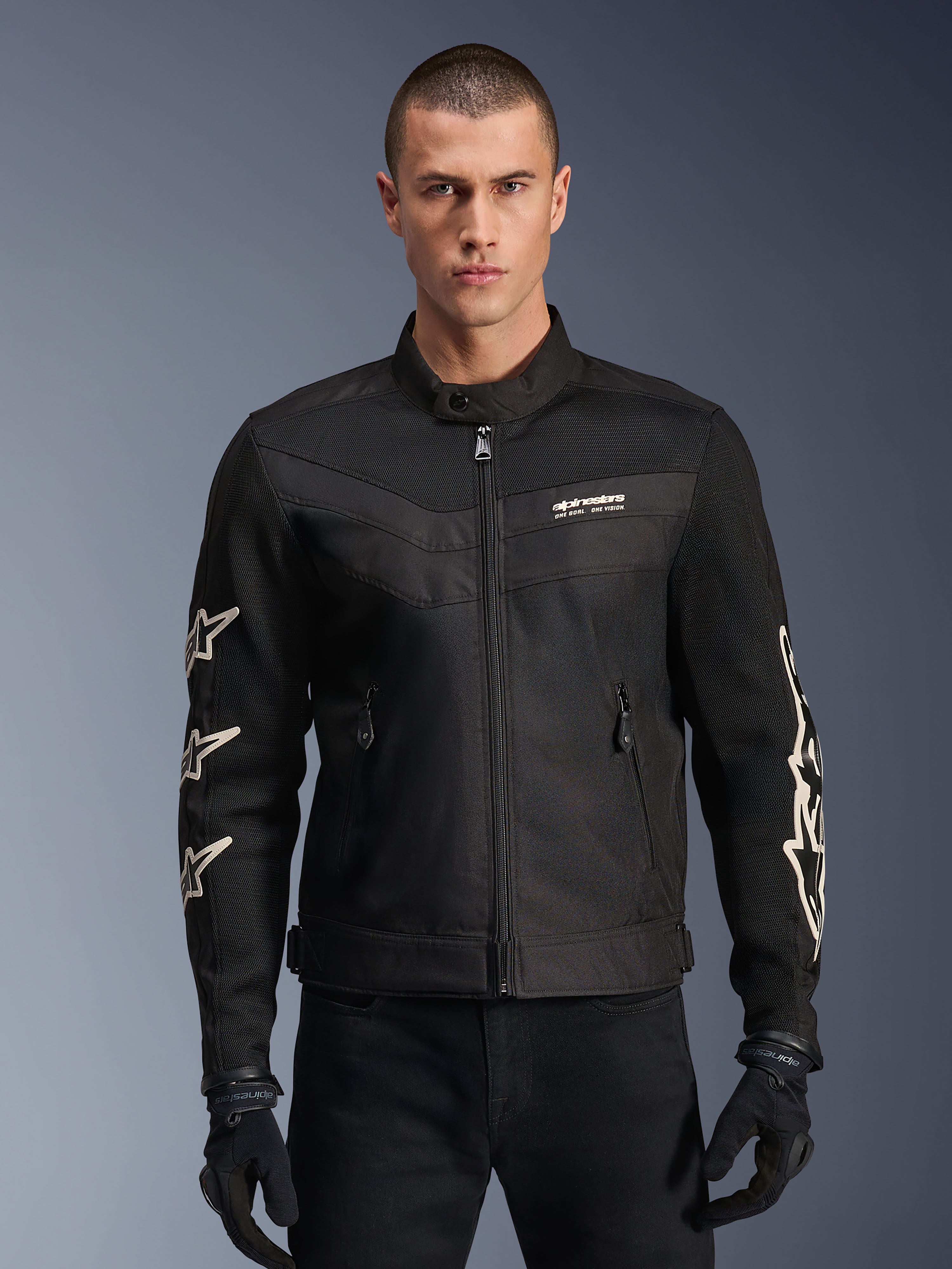 Alpinestars T-Dyno Air Jacket, veste de moto en textile noir, avec graphismes d'étoiles blanches sur les manches et logo sur la poitrine, panneaux en maille pour la ventilation, coupe de motard d'inspiration vintage, portée avec des gants et un pantalon noirs