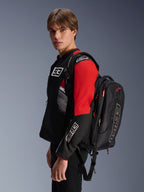 Alpinestars MM93 City Hunter V2 Rugzak, zwart met rode accenten, gedragen door een model in een bijpassende zwarte en rode MM93 motorjas, voorzien van Marc Márquez branding en logo's, urban motorkleding