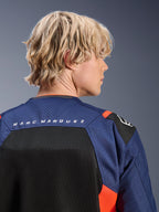 Alpinestars MM93 T-SPS Air V2 Jacke, Navy-Blau und Schwarz mit fluoreszierend roten Akzenten, Nahaufnahme des oberen Rückens mit „MARC MARQUEZ“-Branding, atmungsaktive Mesh-Panels und perforierte Textilkonstruktion, getragen von einem blonden Model.