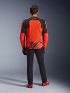 Achteraanzicht van de MM93 T-SPS Air V2 Jas, Red Fluo en Black, textielen motorjas met grote mesh-panelen op de rug voor ventilatie, gedragen met zwarte broek en rood schoeisel, voorzien van Marc Marquez 93-branding