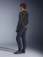 Alpinestars FQ20 T-SPS Air V2 Monster Jas, zwarte textiele motorjas met groene Monster Energy-logo's op de mouwen en witte Alpinestars-branding, gedragen door een model in driekwart achteraanzicht met donkerblauwe jeans en zwarte motorschoenen, urban sport-stijl.