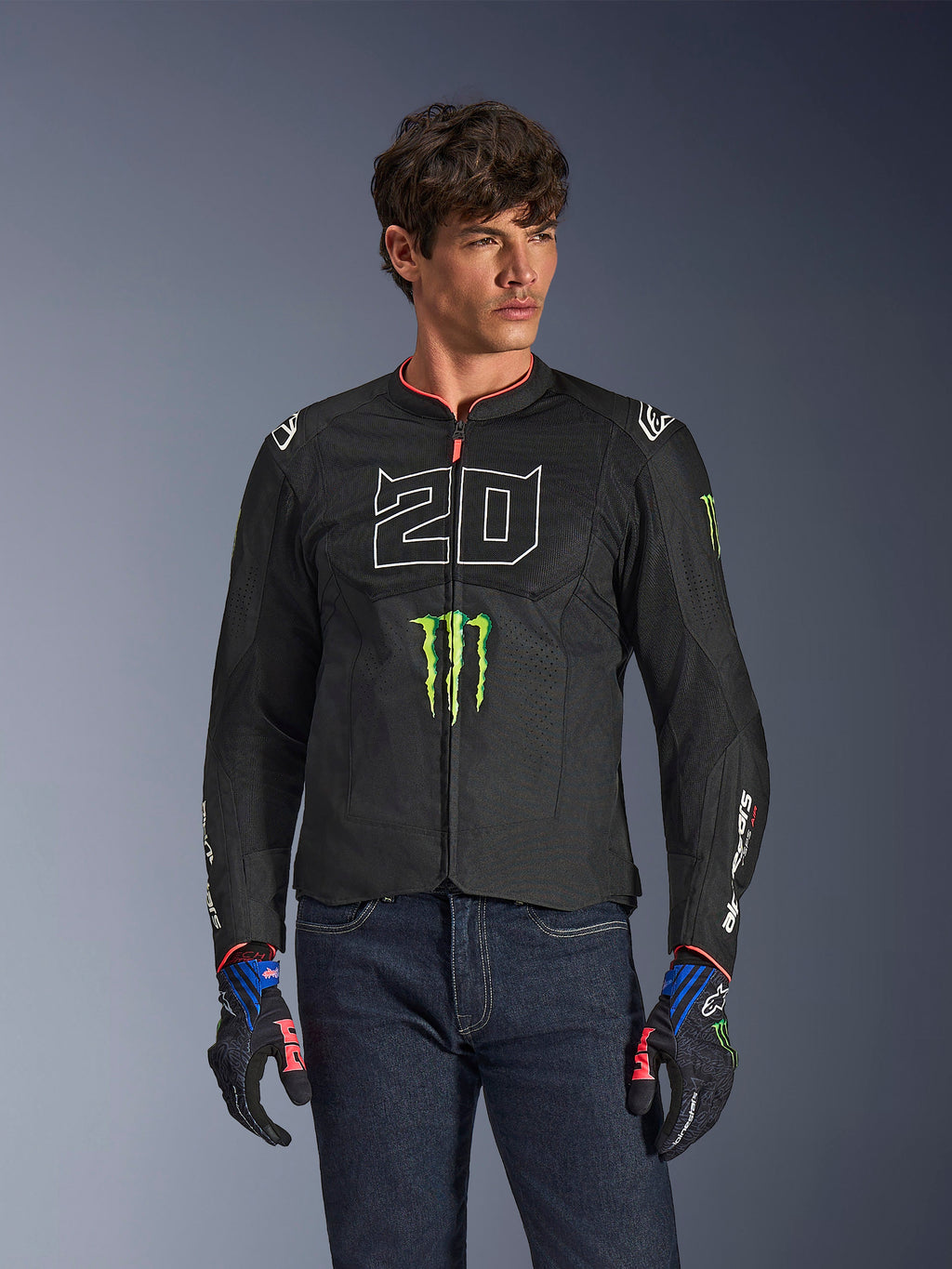 Alpinestars FQ20 T-SPS Air V2 Monster jas, zwarte motorjas met groot wit '20' cijfer en groen Monster Energy-logo, gedragen door een mannelijk model met donkere jeans en bijpassende handschoenen, lichtgewicht mesh-constructie voor stedelijk rijden