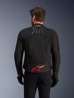 Veste Alpinestars SMX Air, vue arrière, noire avec logo Alpinestars rouge vif dans le bas du dos, dotée d'un panneau en maille technique à haute circulation d'air et du marquage Tech-Air Ready, portée par un pilote avec pantalon et gants noirs