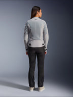 Femme portant la veste Alpinestars Stella C-1 Air couleur argent, vue de dos, dotée de grands panneaux en maille technique pour la ventilation et d'un logo étoile réfléchissant, associée à un pantalon de moto noir et des baskets blanches, équipement de moto urbain contemporain