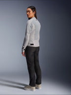 Femme portant la veste Alpinestars Stella C-1 Air en coloris argent, vue de dos et de côté montrant les panneaux en maille technique et le logo réfléchissant sur l'épaule, associée à un pantalon de moto noir et des baskets beiges, esthétique de conduite urbaine contemporaine