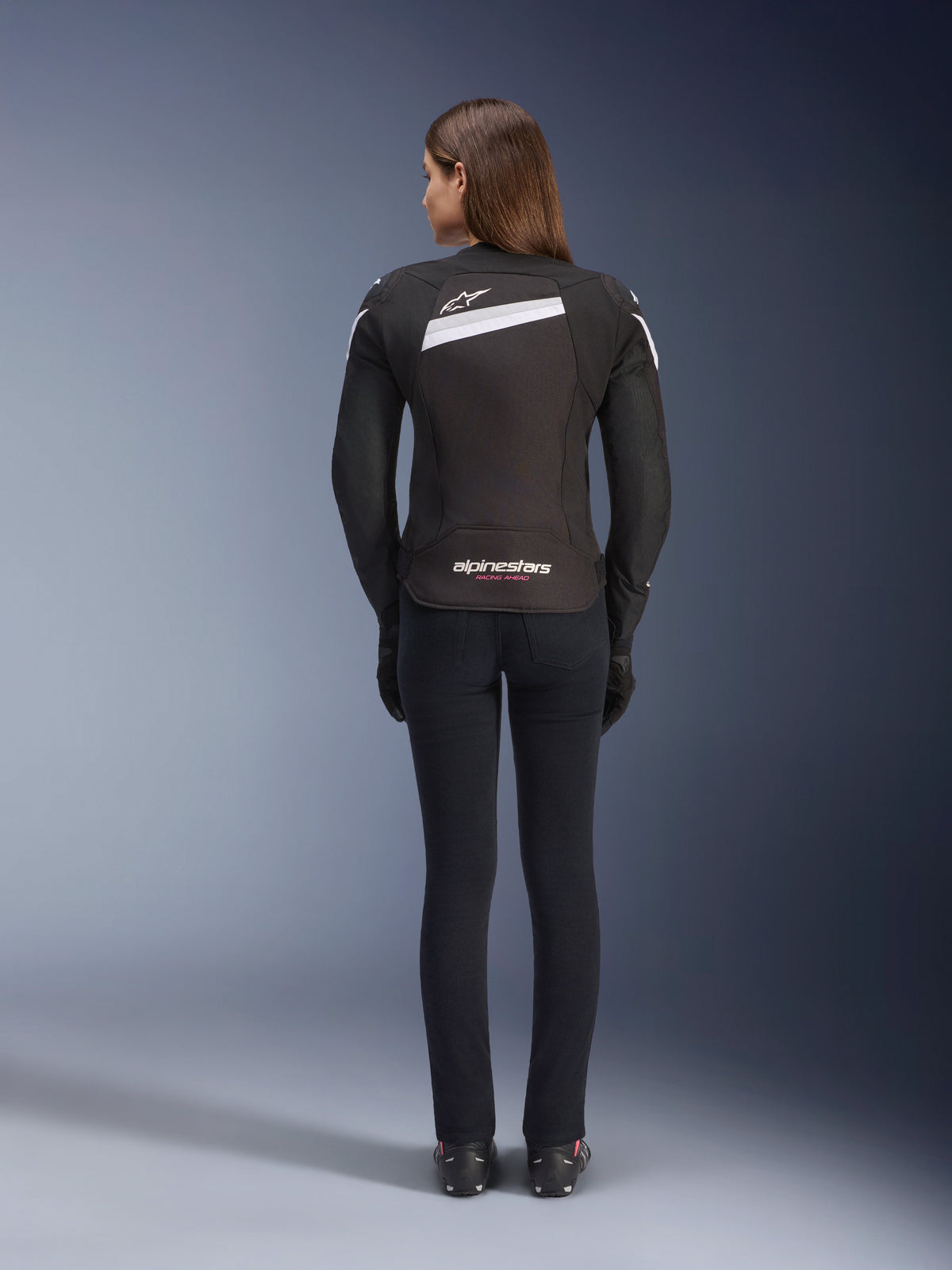 Alpinestars Stella T-GP Plus R V4 Jacket, Women's Textile Motorcycle Jacket, Black and White, rear view showing white accents and logo branding on the back, worn with black pants, sleek sport fit for road performance