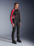 Alpinestars Stella T-Dyno Air Jacke, Damen-Motorradjacke, Schwarz mit leuchtend roten und fuchsiafarbenen Streifen an den Ärmeln, getragen mit schwarzer Motorradhose und Stiefeln, Vintage-inspiriertes Mesh-Design für urbanes Fahren