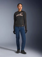 Motarde portant la veste Alpinestars Stella SMX Air, noire avec marquage blanc et rouge fluo, associée à un pantalon de moto en denim bleu et des gants noirs, veste textile ventilée sportive pour la route
