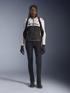 Veste Alpinestars Stella SMX Air, Ice Gray, noir et corail fluo, portée par un mannequin femme avec un pantalon de moto et des gants noirs, dotée d'un châssis en mesh et de sliders de protection aux épaules, équipement de moto de sport pour femme