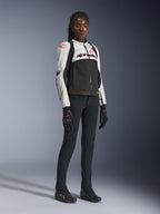 Veste Alpinestars Stella SMX Air pour femme, coloris Gris Glace, Noir et Corail Fluo, portée par un modèle féminin avec un pantalon et des gants de moto noirs, construction en mesh et logos rouge corail, équipement de moto sportif pour femme