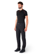 Pantalon Alpinestars Alden, pantalon de moto urbain, noir, textile softshell à coupe régulière, porté par un mannequin avec une couche de base noire et des chaussures de moto, doté d'une ceinture à fermeture magnétique et de poches zippées.