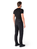 Pantalon Alpinestars Alden, noir, pantalon de moto urbain présenté de dos sur un mannequin, porté avec une couche de base noire à manches courtes et des chaussures de moto noires, avec des détails matelassés et le marquage réfléchissant MO.ST.EQ. sur l'empiècement arrière.