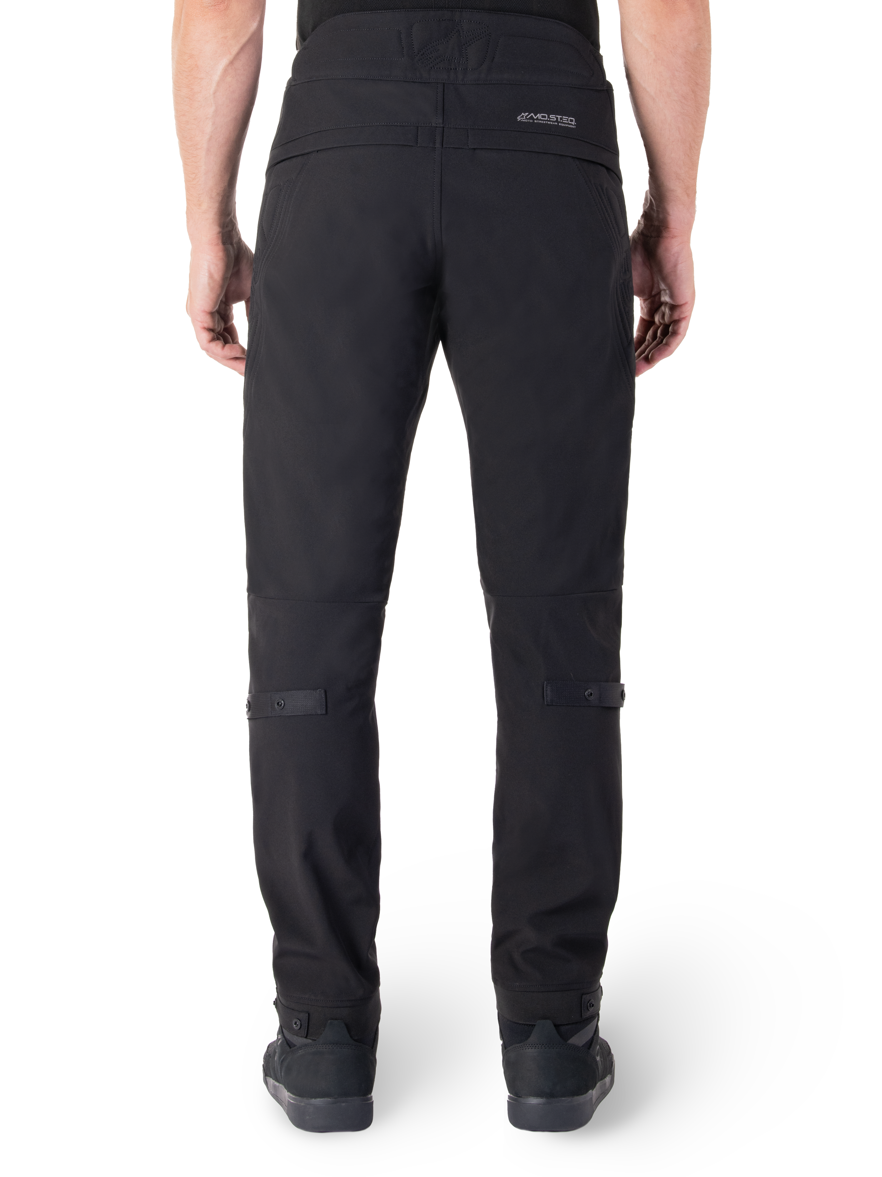 Pantalon Alpinestars Alden, pantalon de moto urbain noir, vue arrière, avec mot-symbole réfléchissant MO.ST.EQ. sur l'empiècement arrière, coupe ajustée sous le genou et boutons-pression de réglage du volume aux mollets et aux chevilles, design textile technique d'inspiration streetwear.