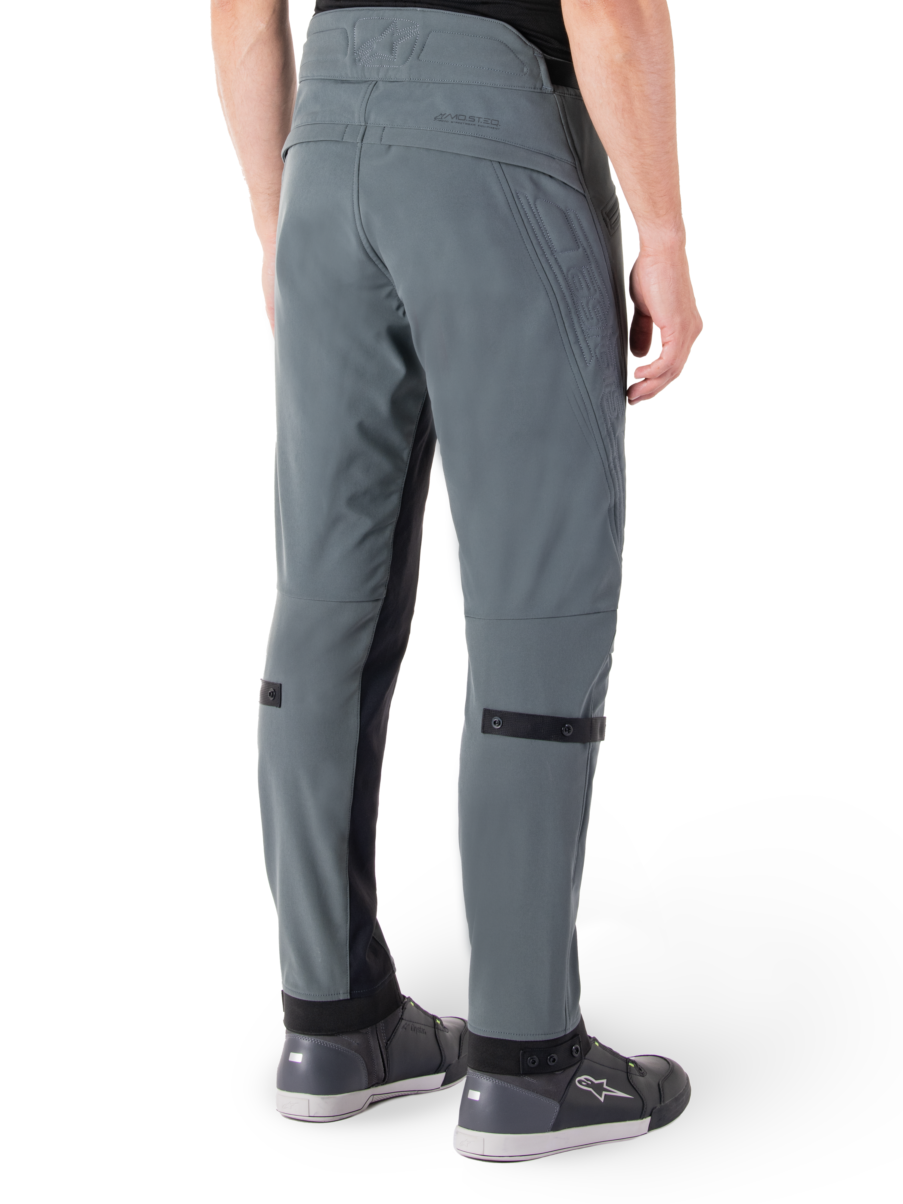 Alpinestars Alden broek, Urban Gray, achteraanzicht, op streetwear geïnspireerde technische motorbroek met gewatteerde details in de taille en zwarte kuitbanden, gecombineerd met grijze motorschoenen, moderne stedelijke motoruitrusting