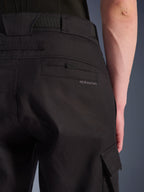 Alpinestars Flex-AST Cargo Broek in het zwart, urban motorbroek, close-up van de achterzijde met gedetailleerde achterzak, subtiele branding, grote riemlussen en een cargozak aan de zijkant, vervaardigd uit duurzaam stretchtextiel