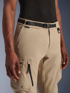 Alpinestars Flex-AST Cargo Pants - Short, Light Beige, close-up view of waist and thigh, featuring a black adjustable belt with Alpinestars branding, metal D-ring, and functional cargo pockets with zippers and snap flaps, urban contemporary motorcycle gear