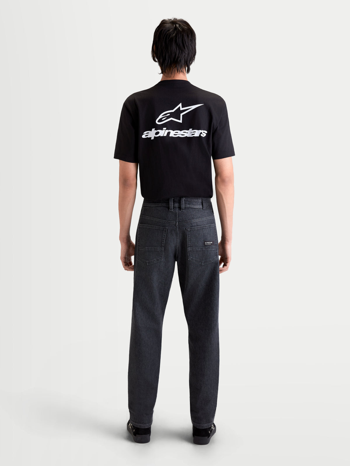 Alpinestars Flex Ast 7 Denim Pantalons Short, pantalon de moto urbain pour homme en noir délavé, vue de dos sur un modèle portant un t-shirt noir, montrant la construction en denim technique monocouche et la coupe fuselée régulière